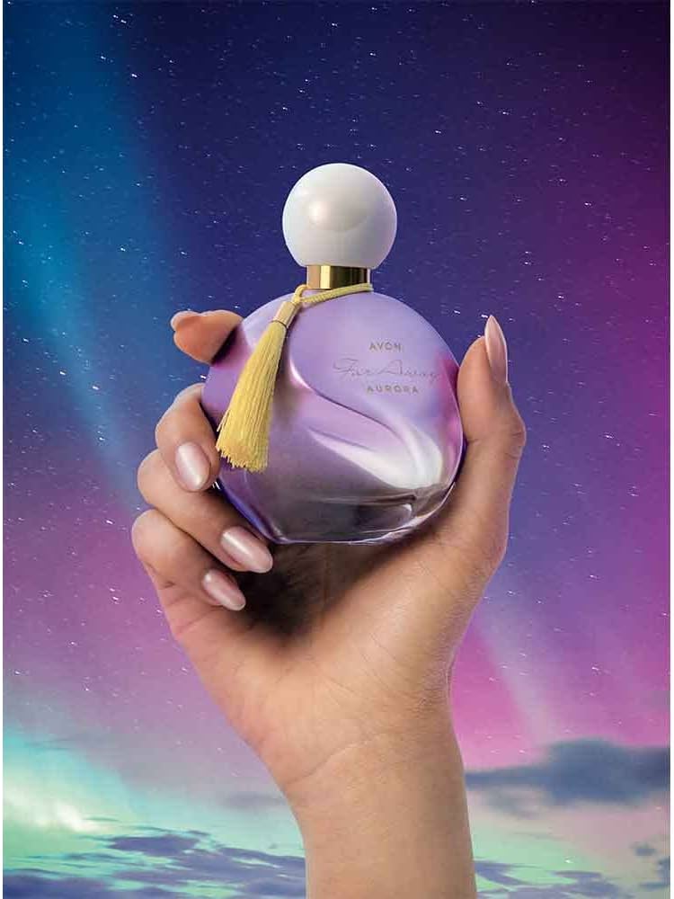 Woman holding Avon far away aurora perfume in hand