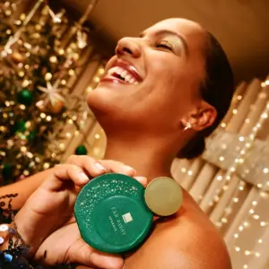 a happy female model holding the avon far away perfume green bottle
